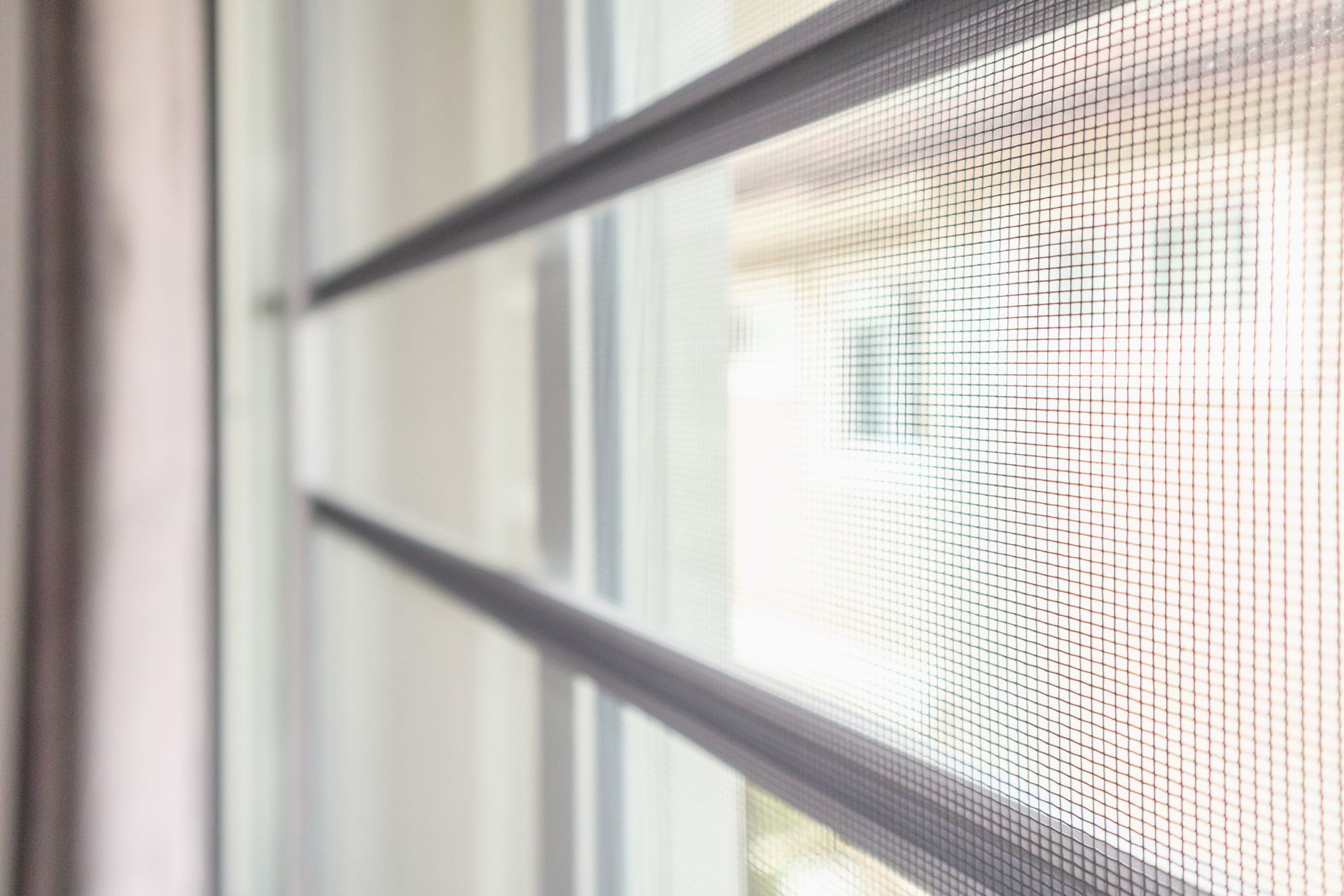 A close up of a mosquito screen on a window.