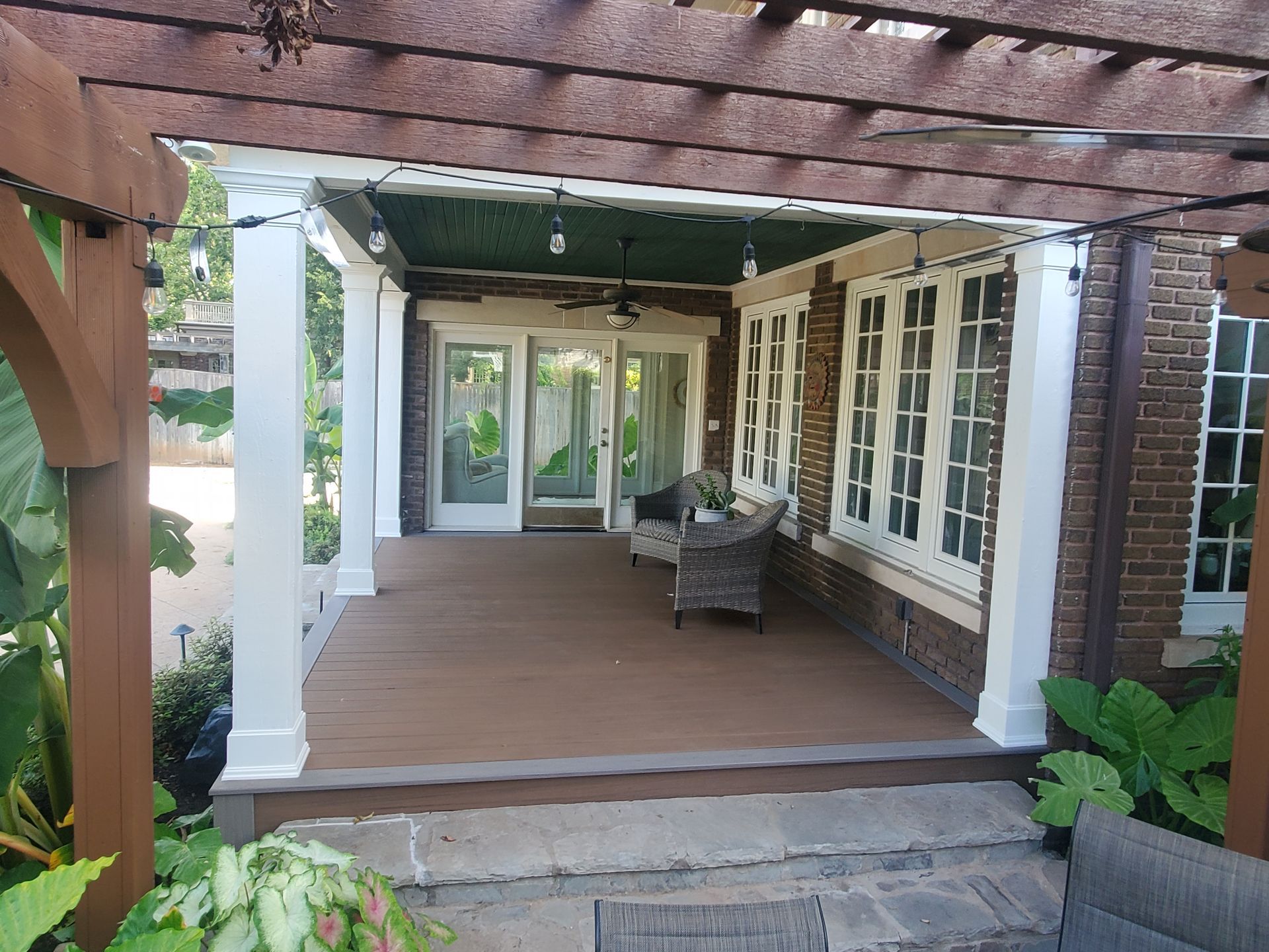 A large covered porch with a pergola and chairs on it.