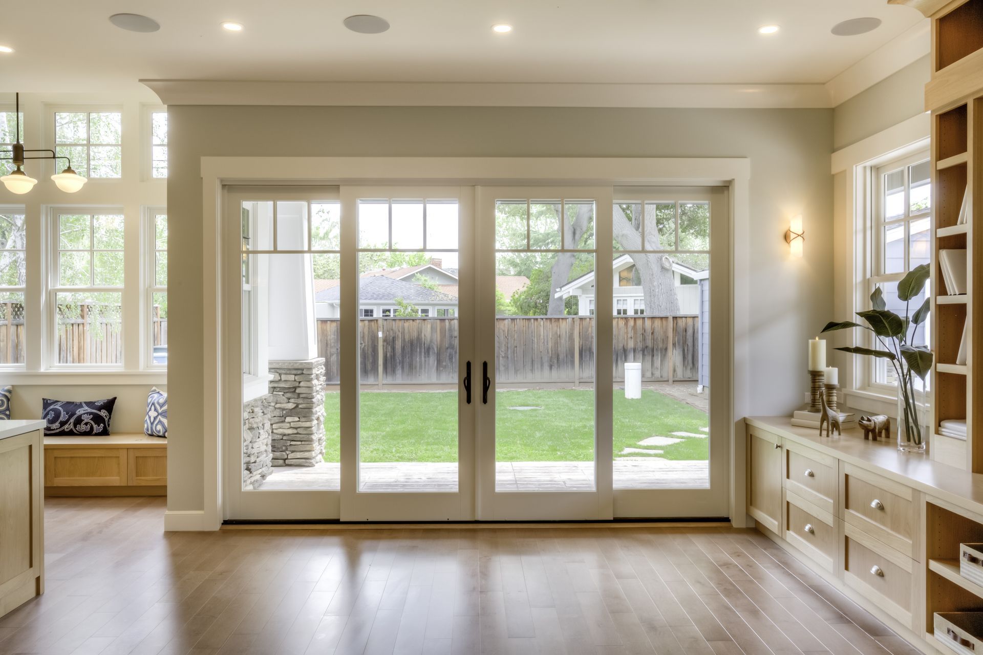 A living room with a lot of windows and sliding glass doors leading to a backyard.