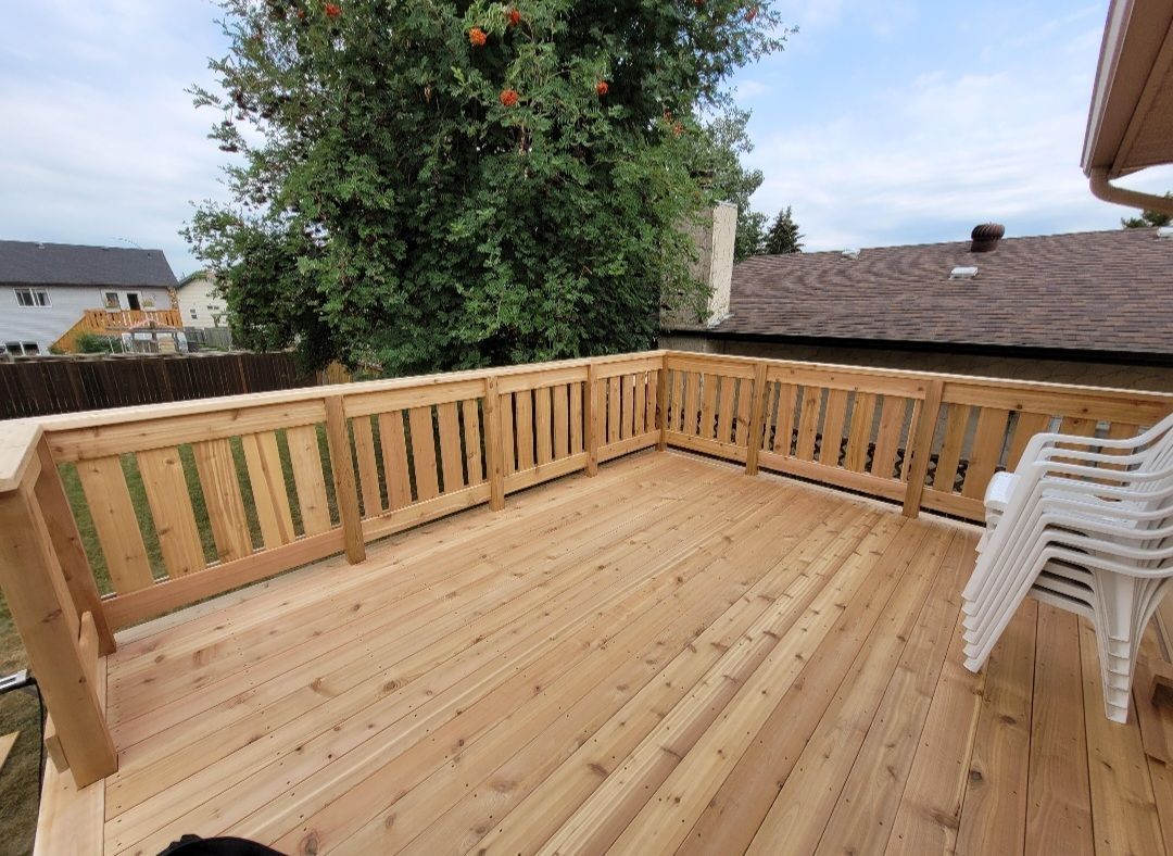 A wooden deck with a fence and chairs on it.