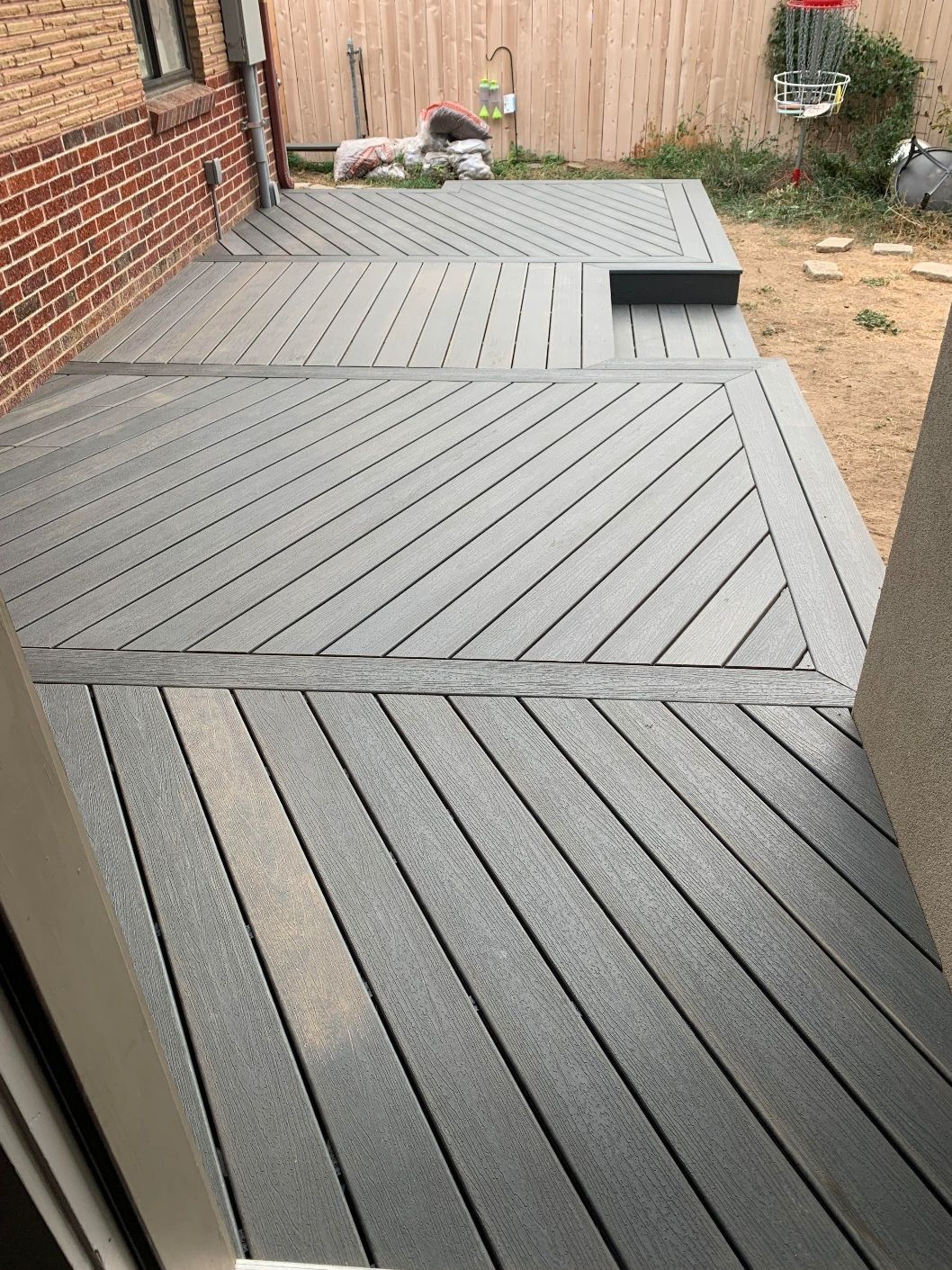A gray deck with a wooden fence in the background