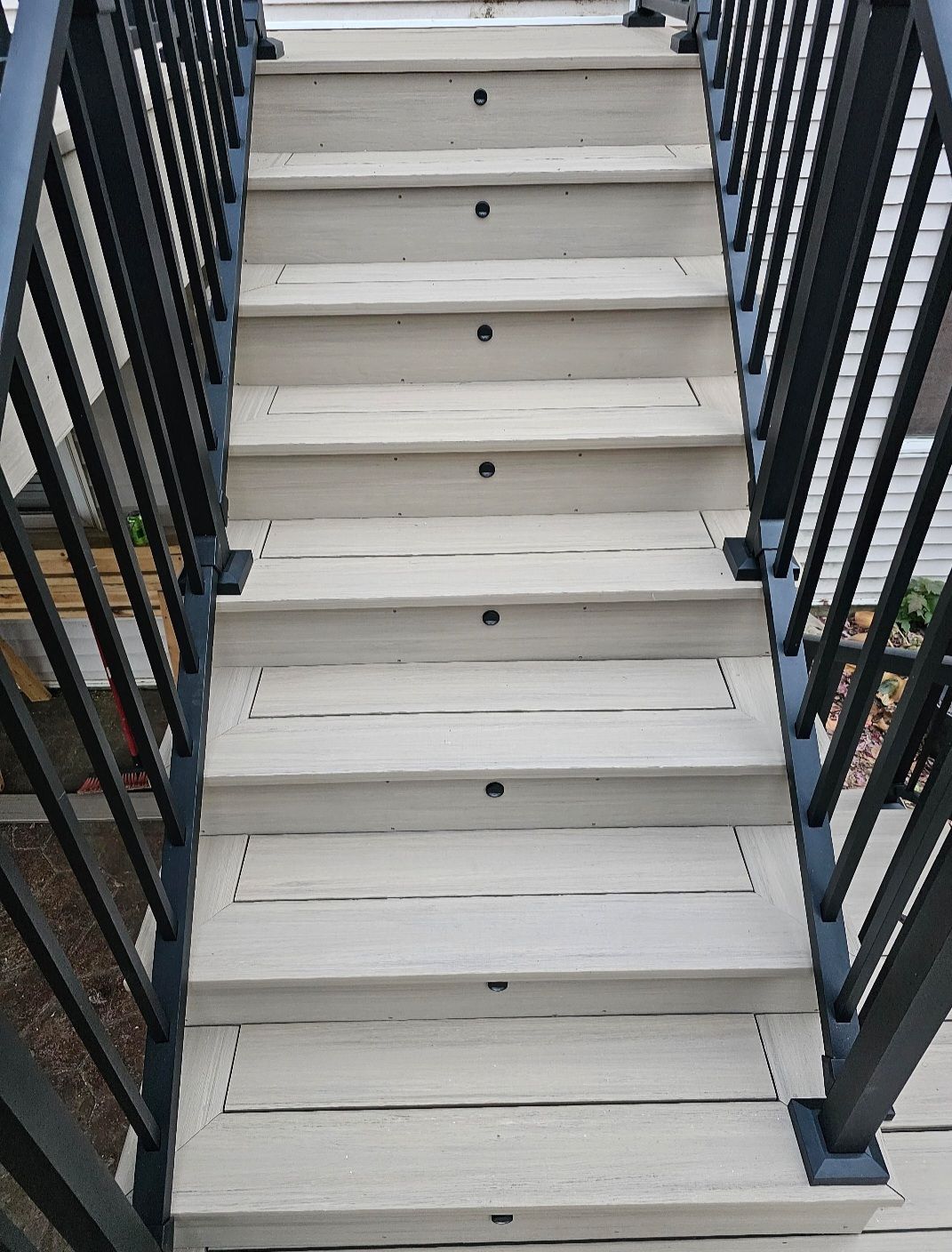 A set of stairs leading up to a deck with a black railing.