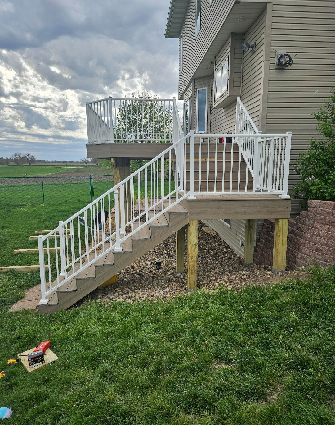 There is a deck with stairs leading up to it and a white railing.