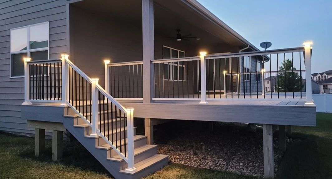 A deck with stairs leading up to it is lit up at night.