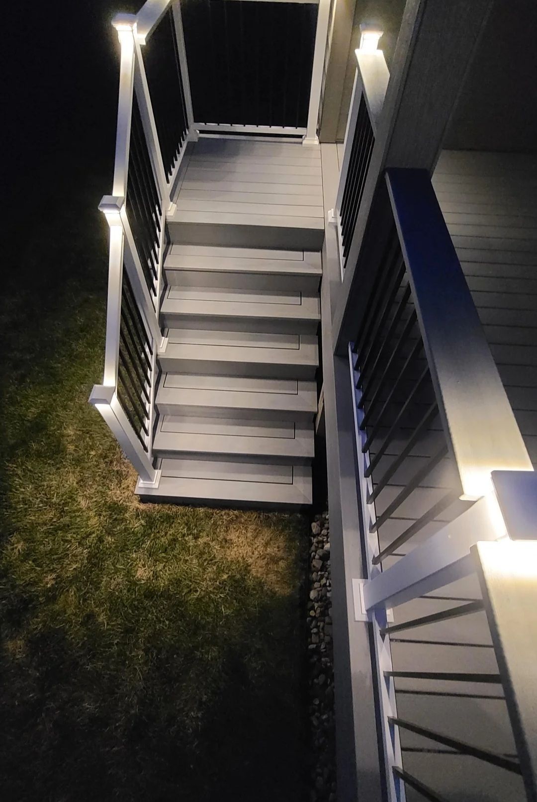 A deck with stairs leading up to it is lit up at night.