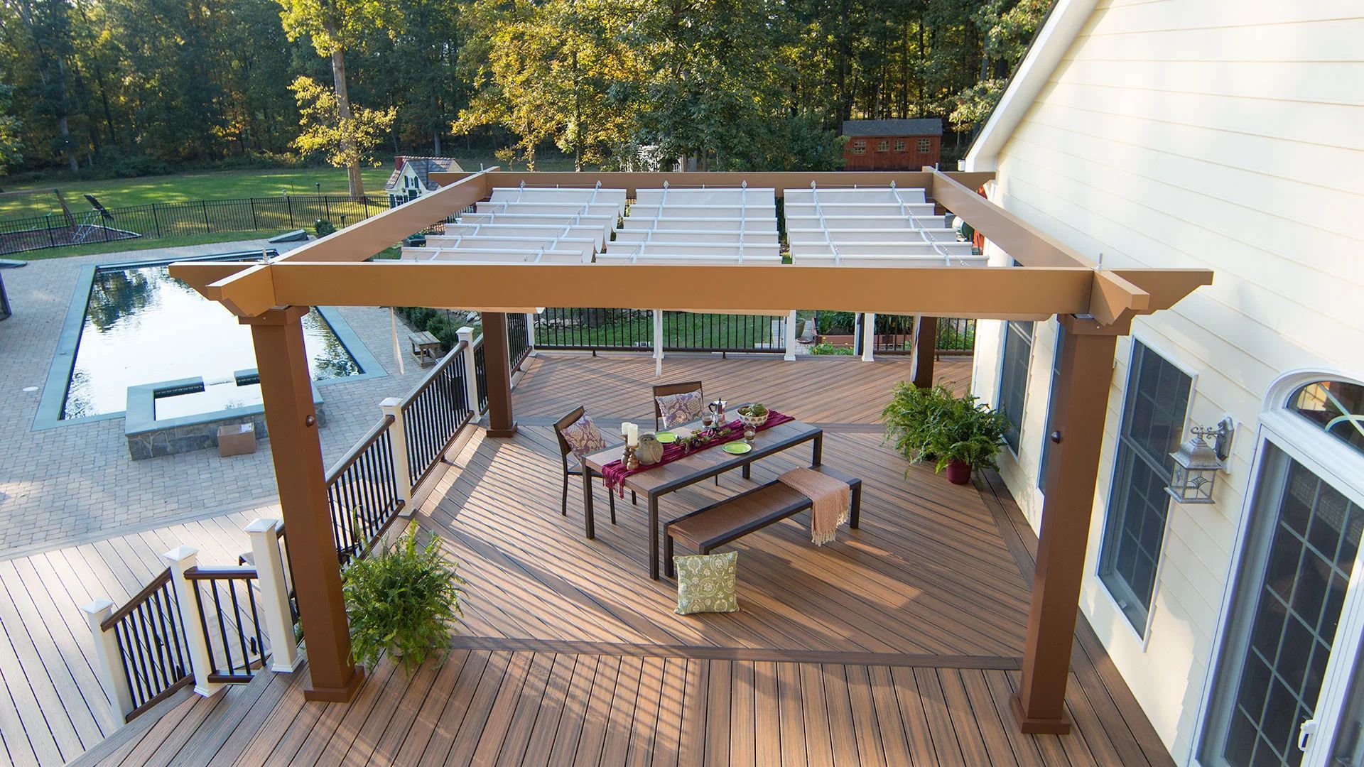 An aerial view of a deck with a pergola and a table and chairs underneath it.