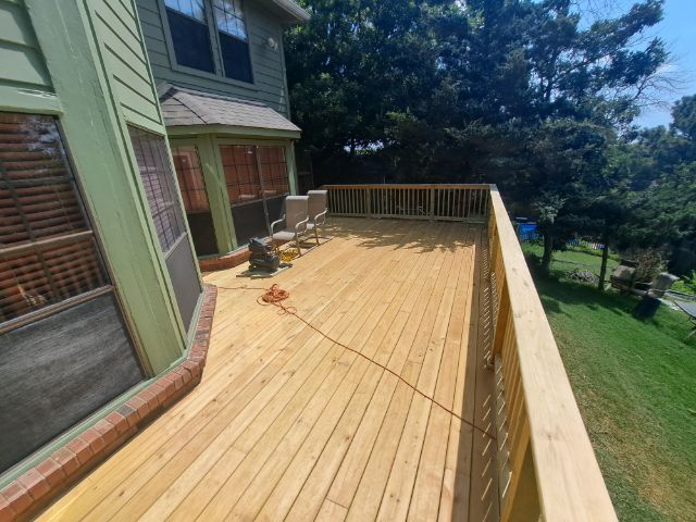 A large wooden deck is sitting on the side of a house.