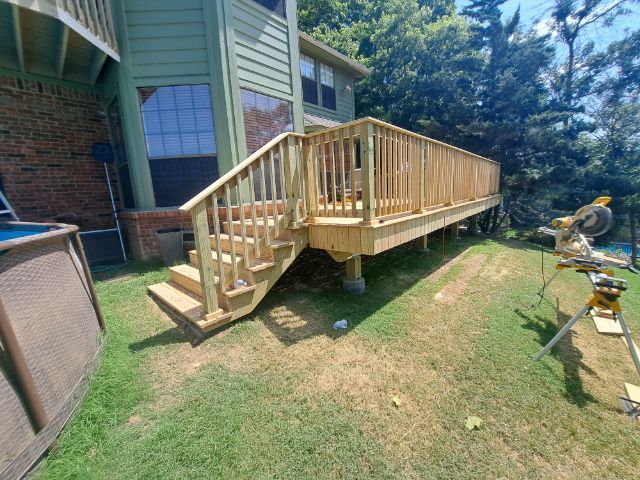 A wooden deck with stairs is being built in the backyard of a house.