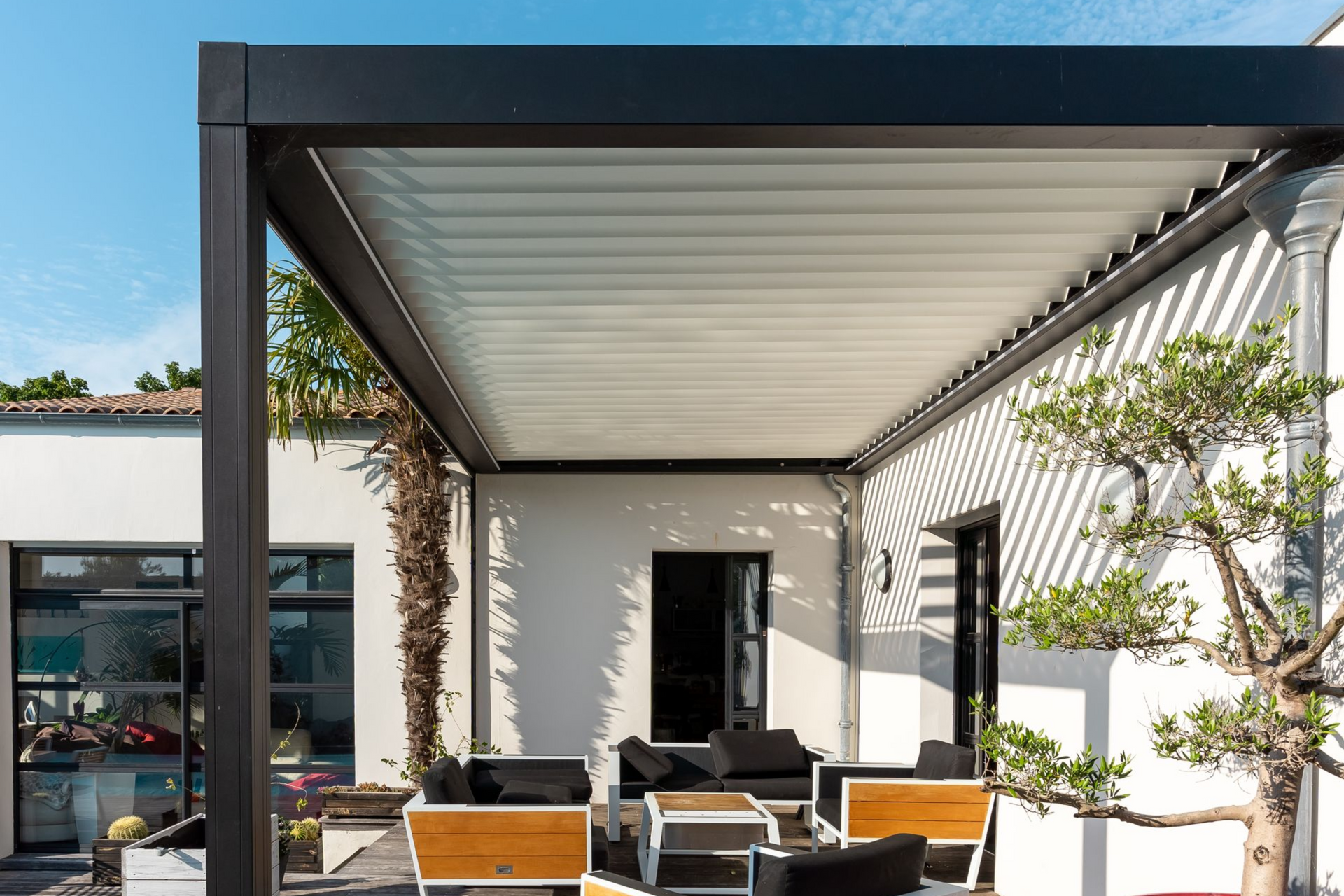 There is a pergola with chairs and a table underneath it.