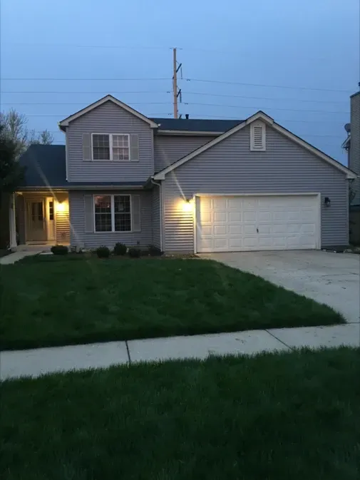 A house with a white garage door is lit up at night