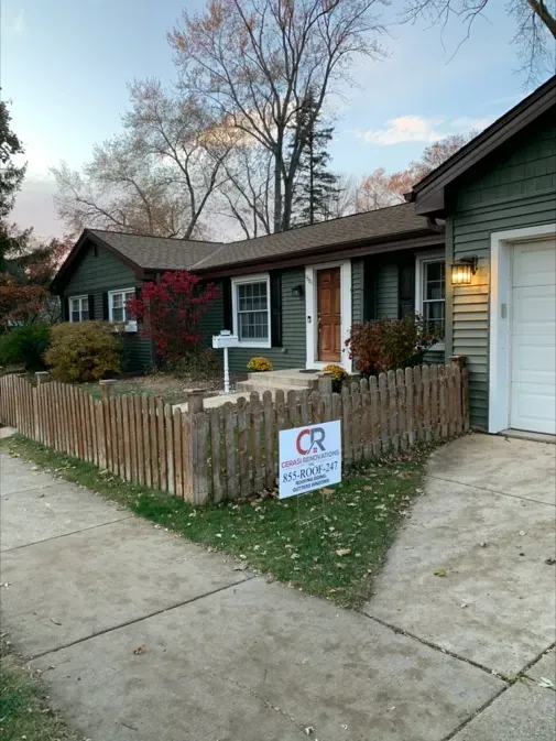 A house with a wooden fence and a sign in front of it.