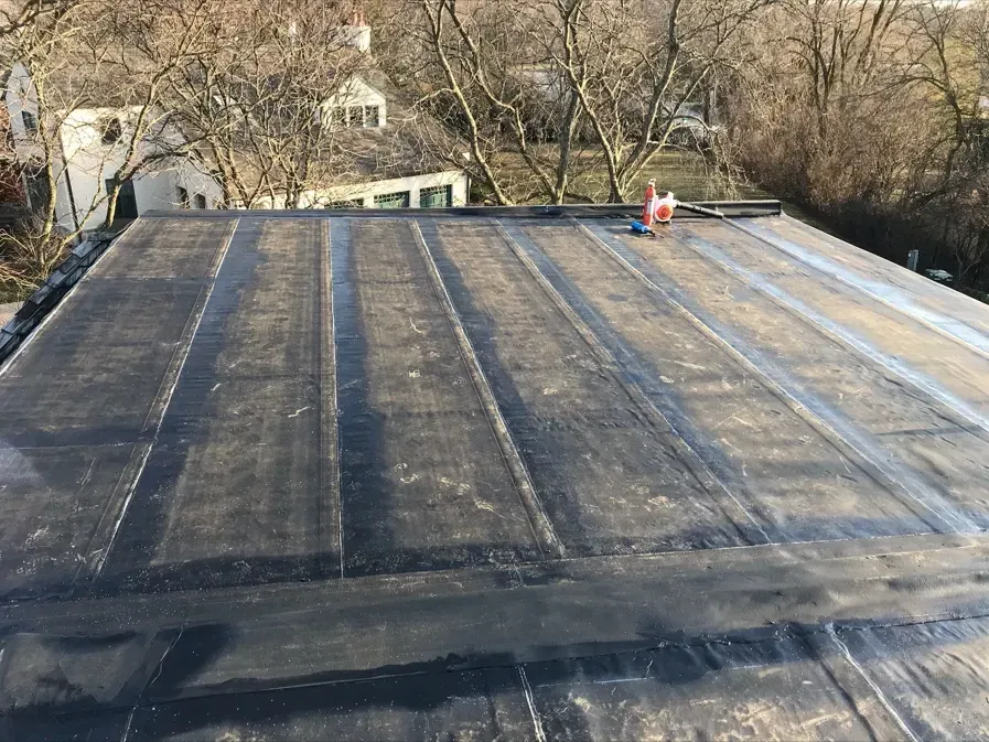 A black roof with a few trees in the background.