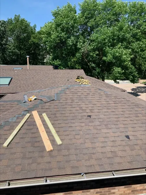 A roof with a few pieces of wood on it and trees in the background.