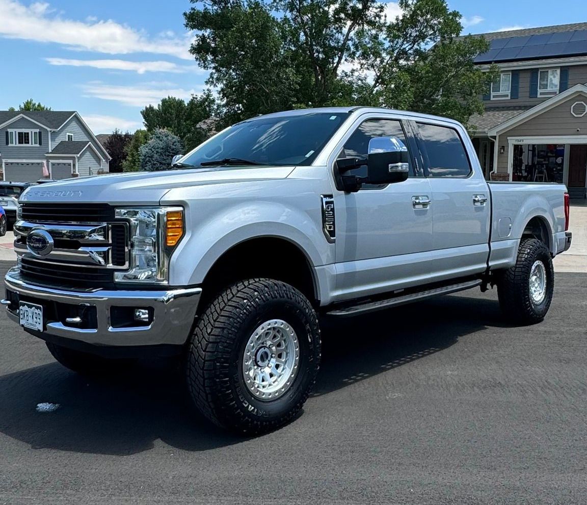 A silver ford f250 pickup truck is parked in front of a house.