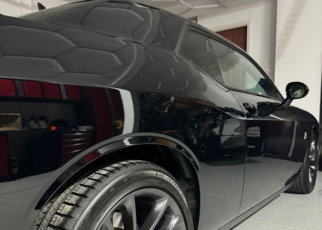 A black dodge challenger is parked in a garage