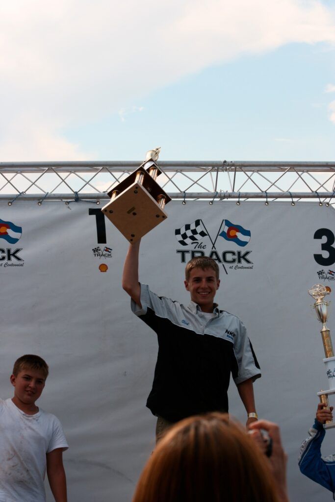 A man is holding a trophy in front of a sign that says track