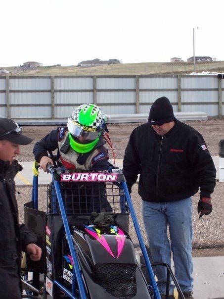A man in a green helmet sits in a burton vehicle