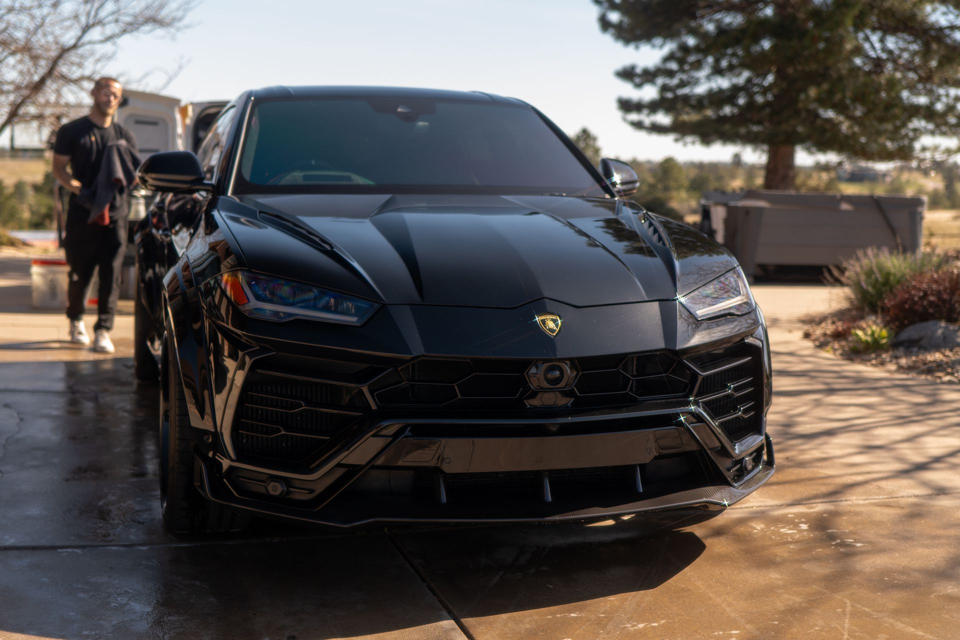 A red tesla model x with its doors open is parked in a driveway.