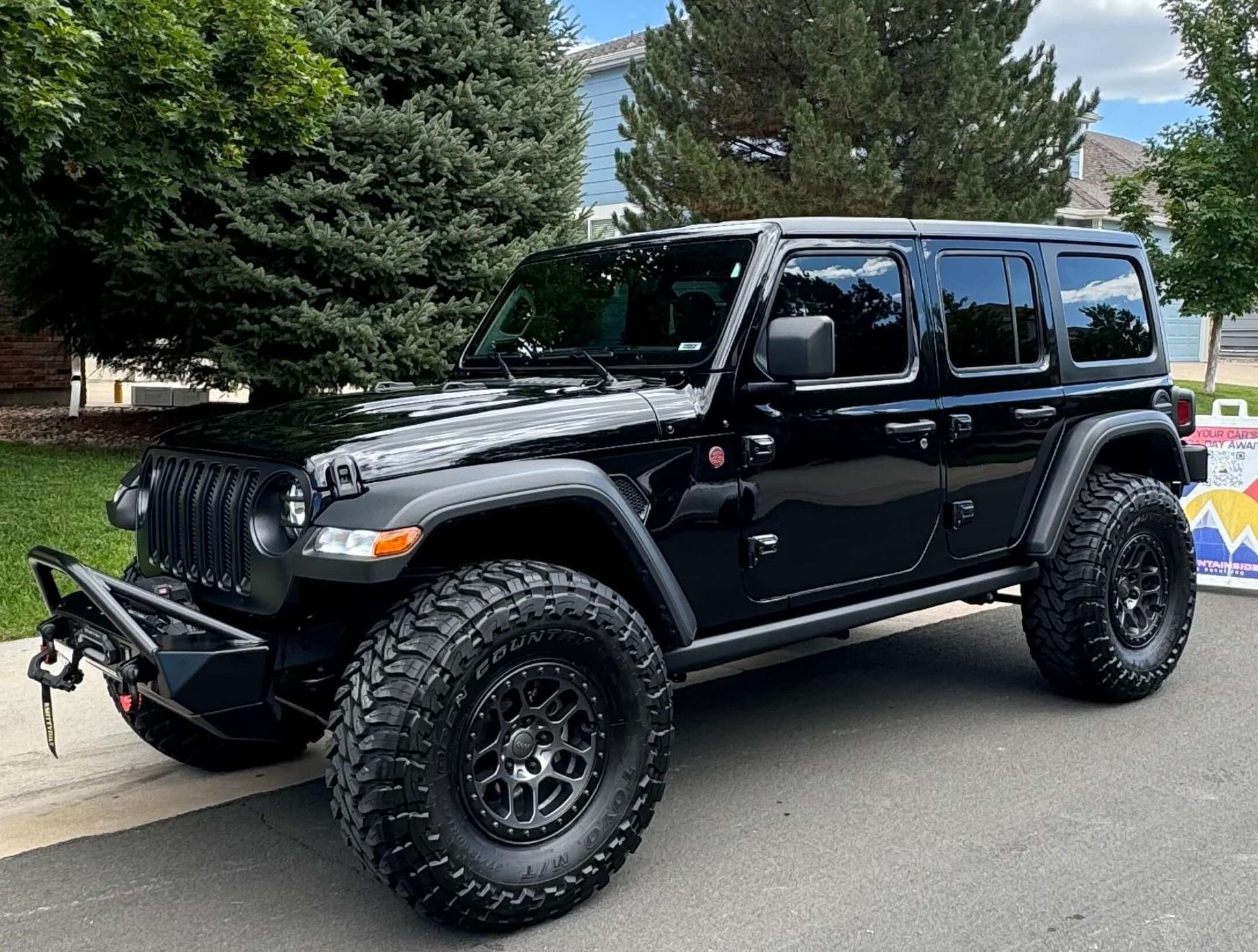 Black GMC Sierra Denali truck parked outside a building on a sunny day.