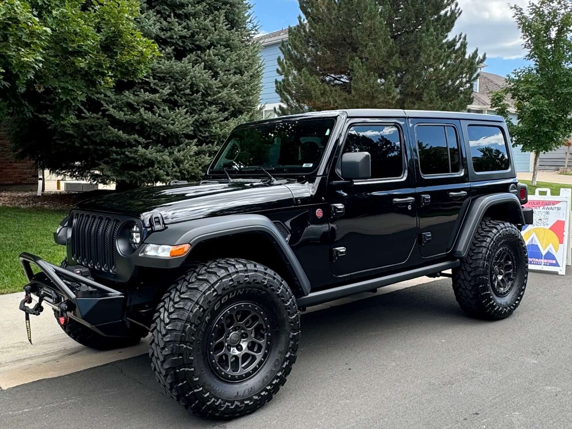 A black jeep wrangler is parked on the side of the road.
