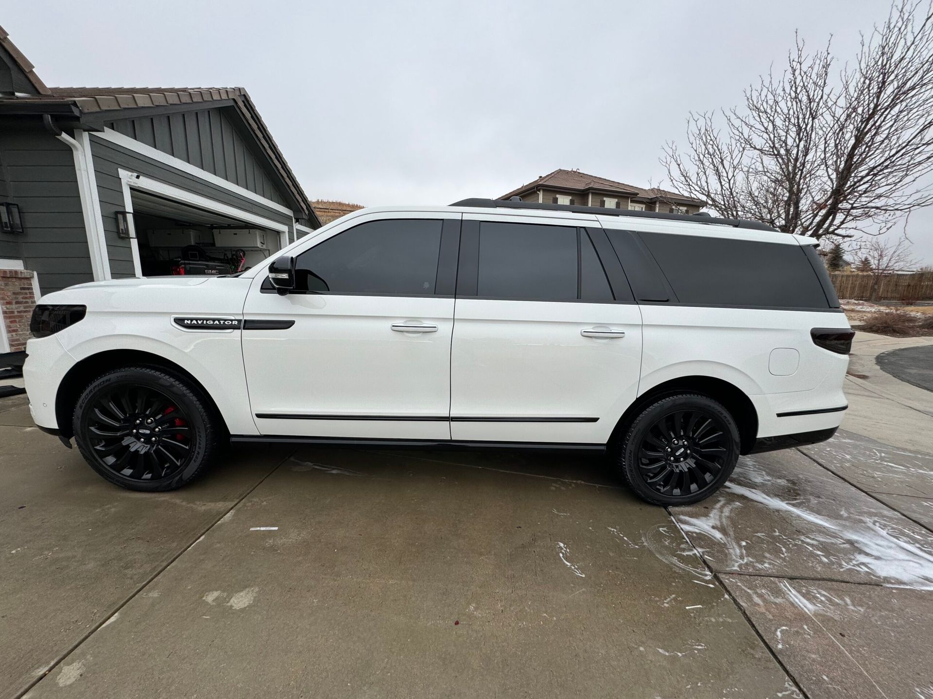 A white suv is parked in front of a house.