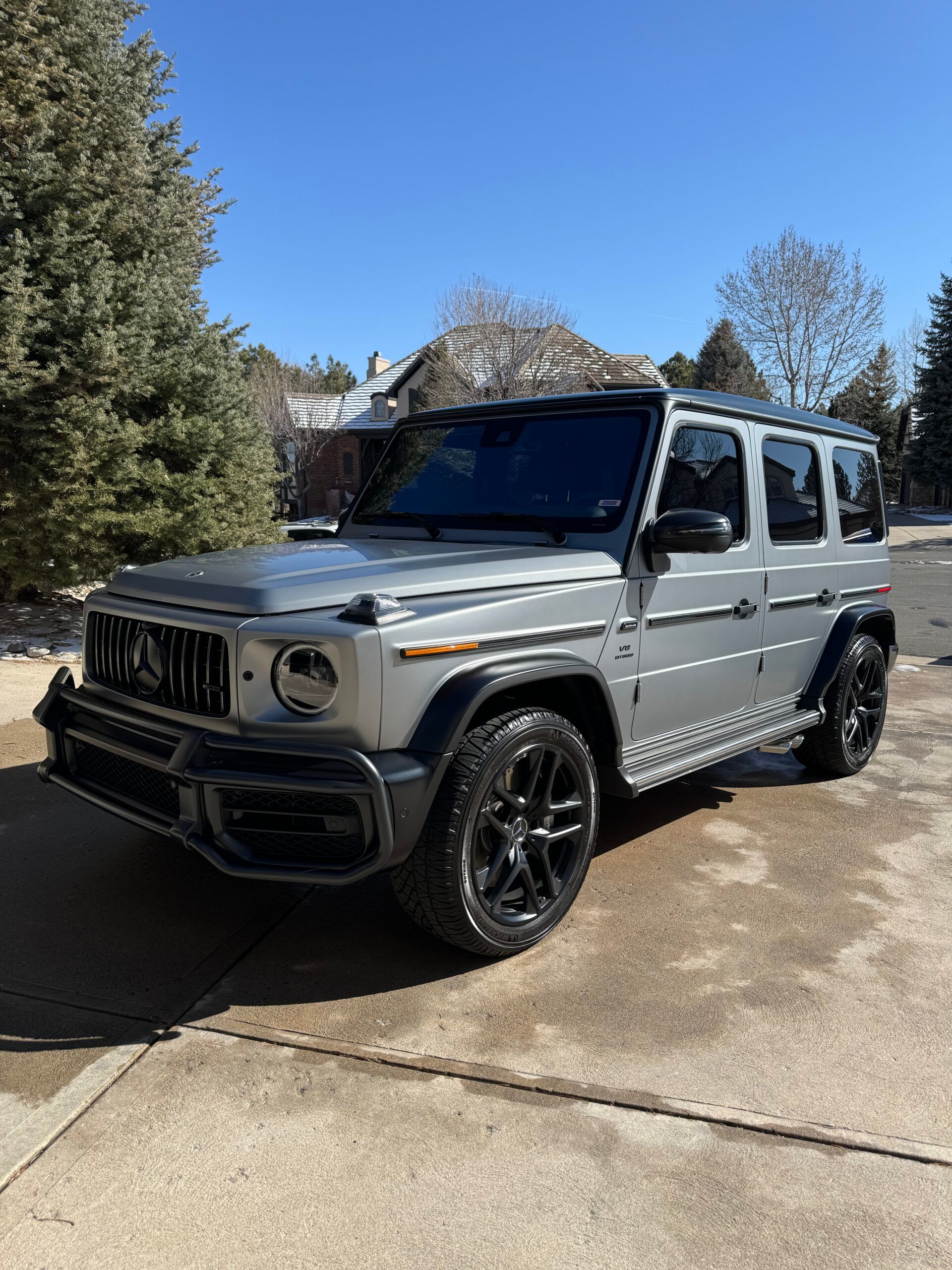 A silver mercedes benz g63 amg is parked in a driveway.