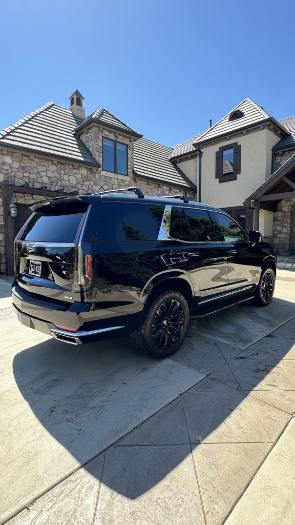 A black suv is parked in front of a large house.
