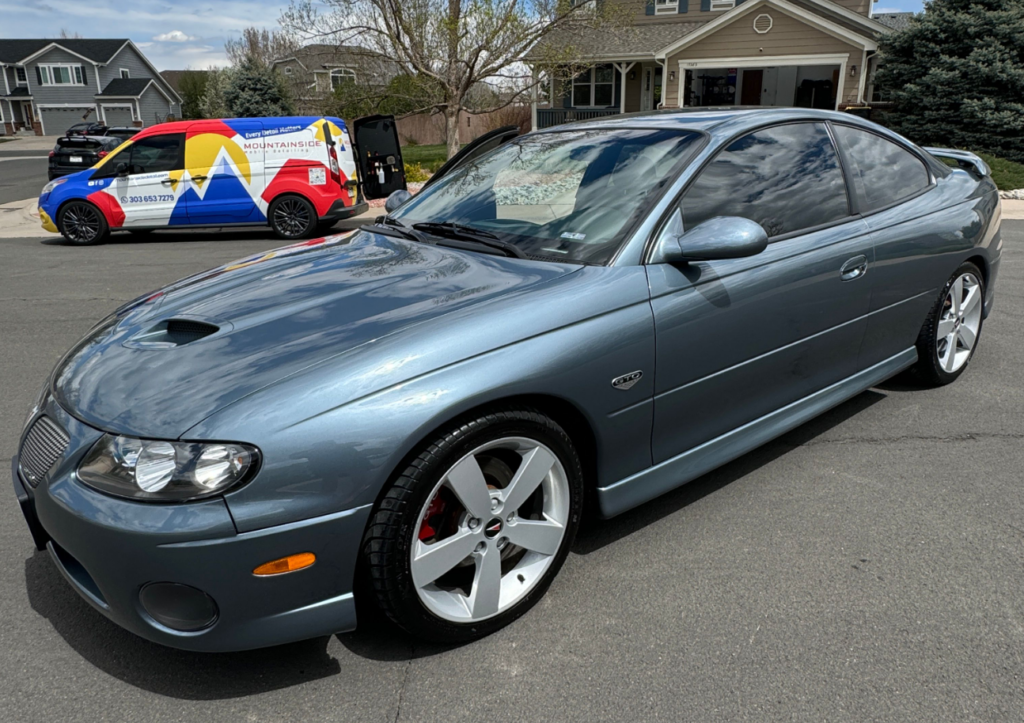 A blue sports car is parked in front of a house.