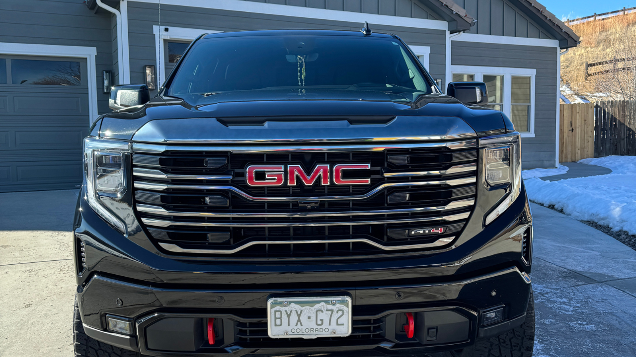 A black gmc truck is parked in front of a house.