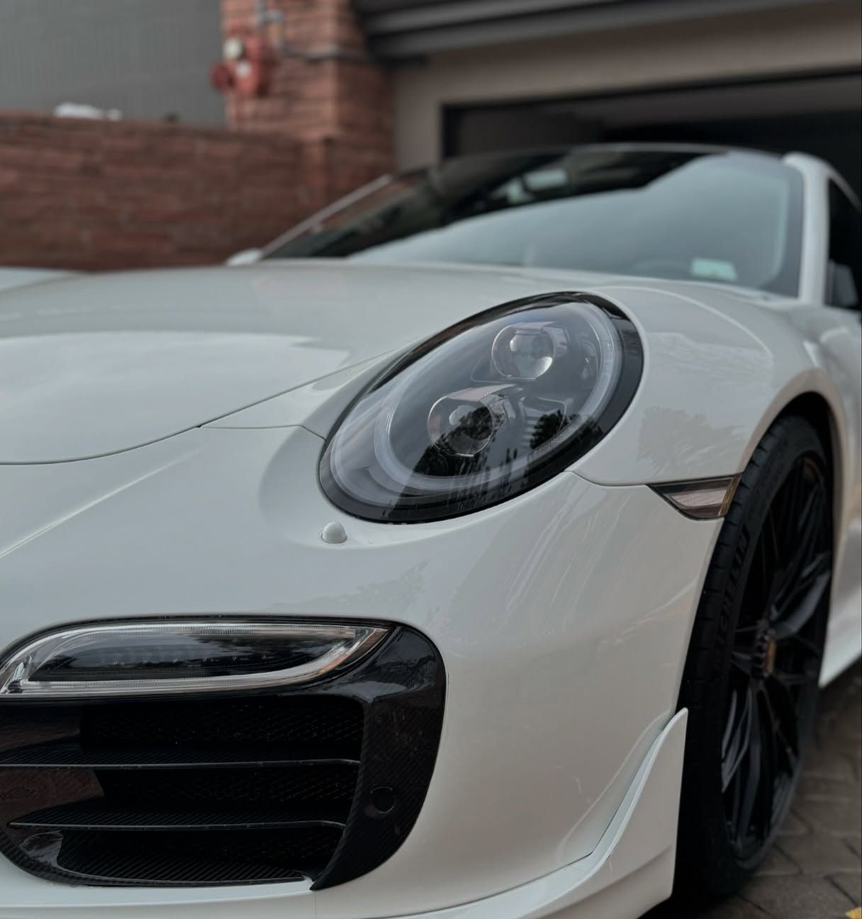 A white sports car is parked in front of a garage