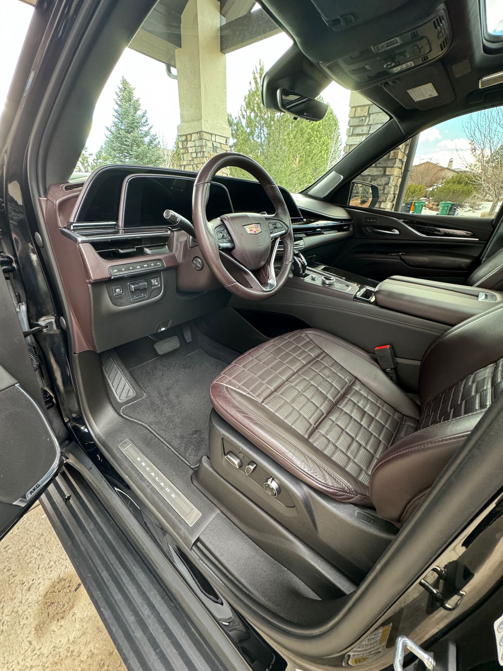 The interior of a black car with the door open and the steering wheel visible.