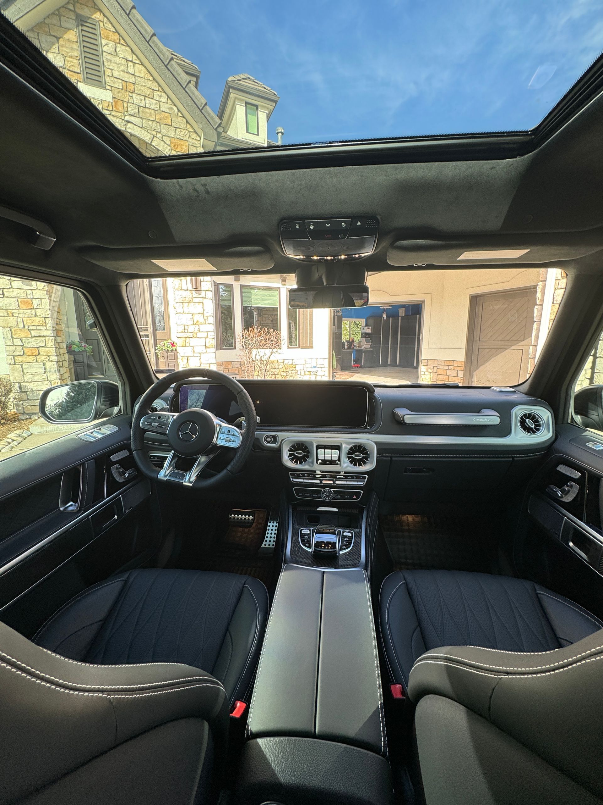 The inside of a car with a sunroof and a steering wheel.