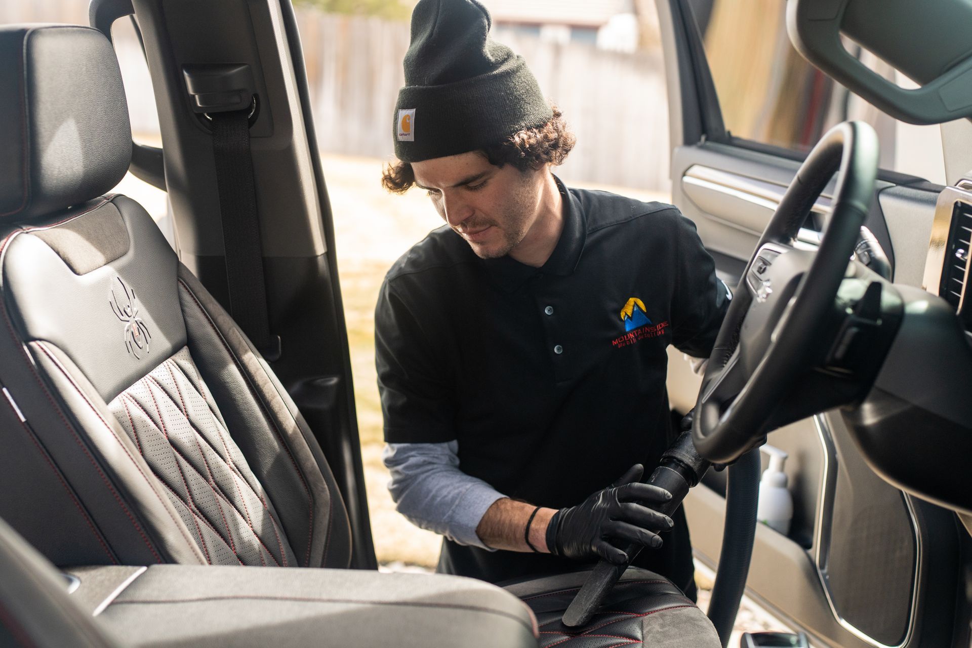 A man is cleaning the seats of a car with a vacuum cleaner.