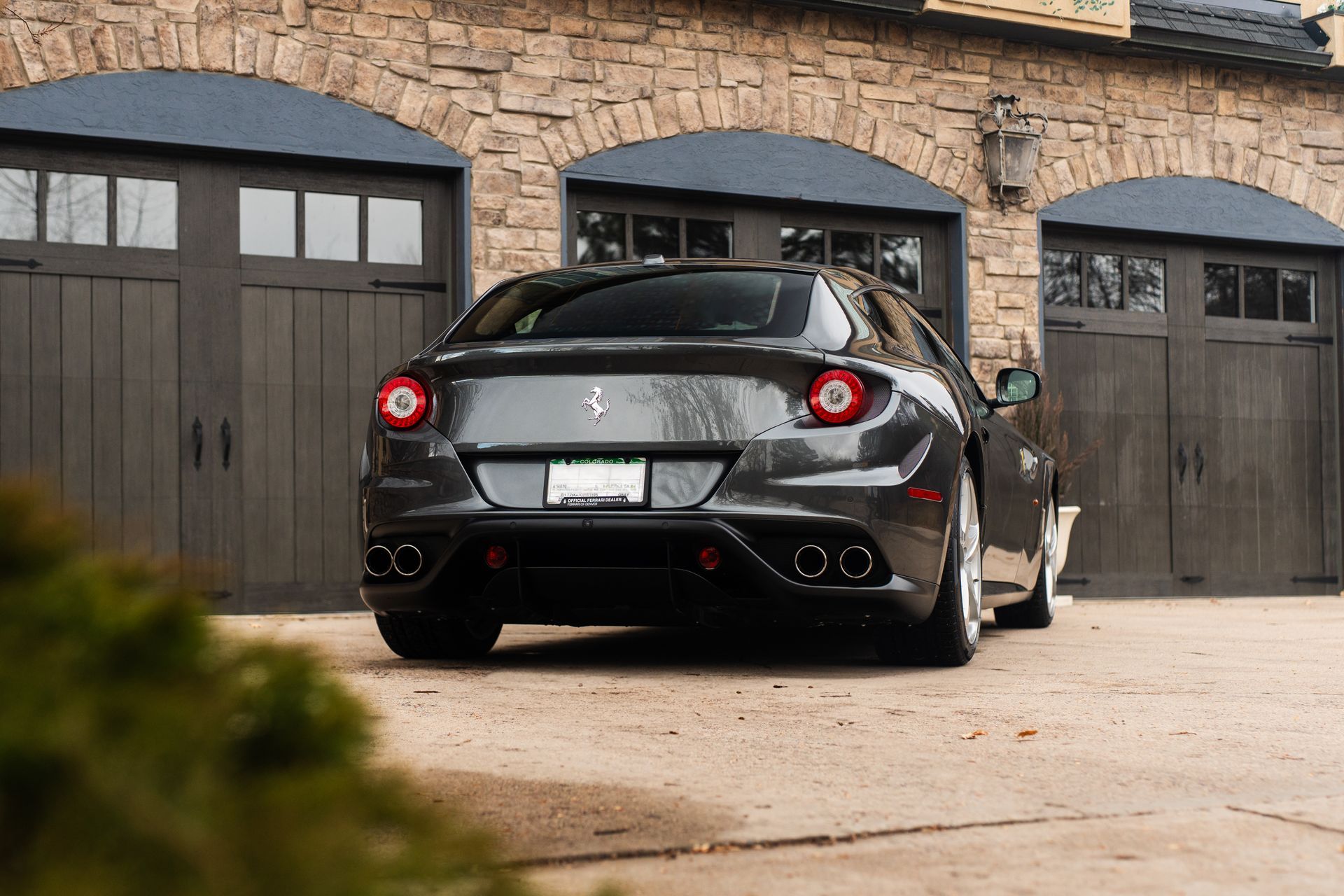A gray ferrari is parked in front of a garage.