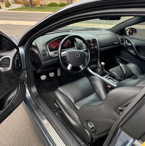 The interior of a car with the door open and the steering wheel visible.