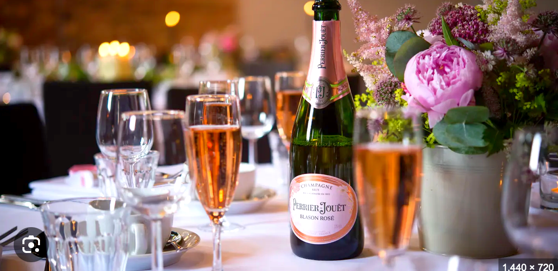 Table setting with champagne bottle, glasses, and floral arrangement.