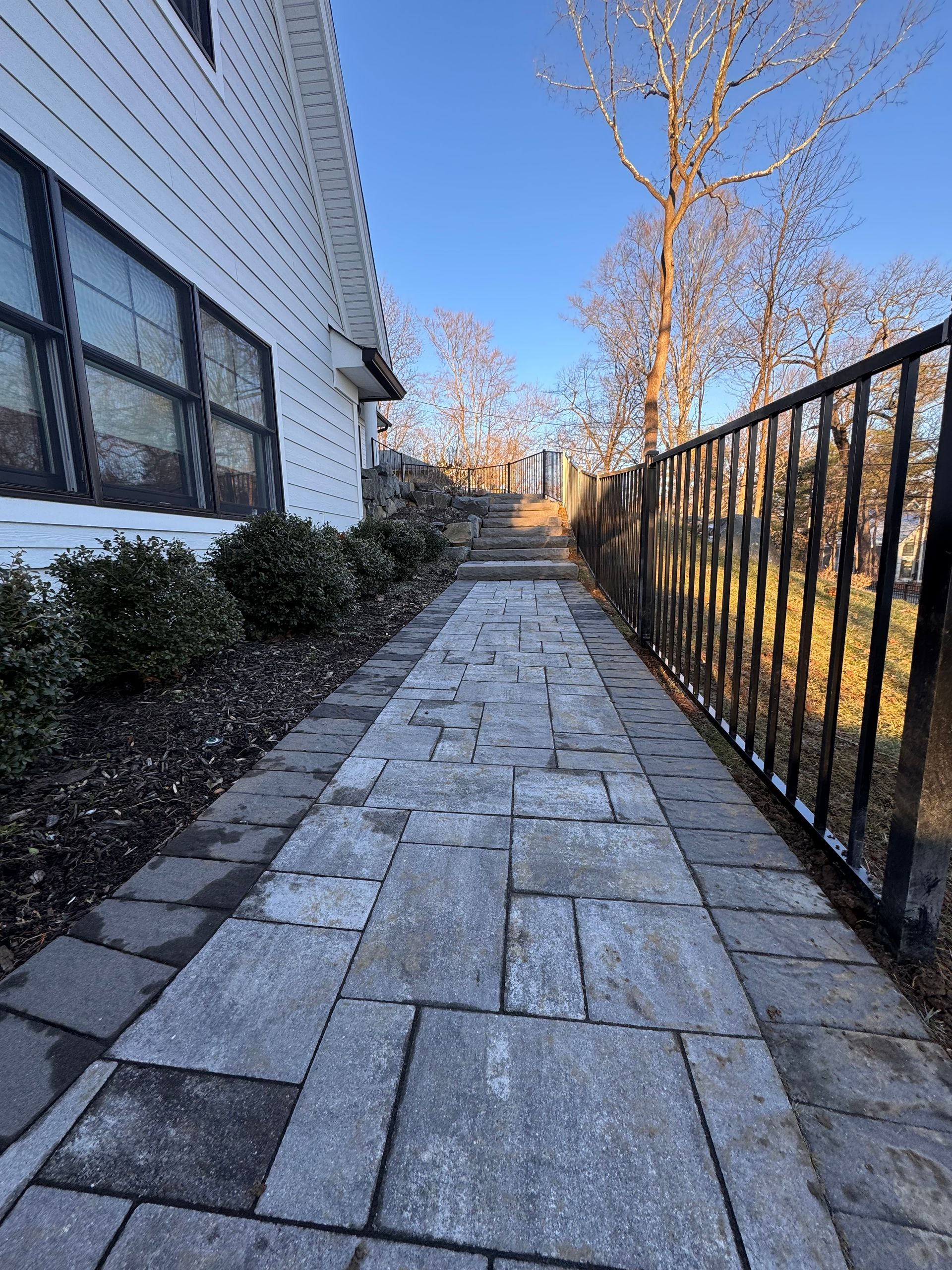 A man wearing a welding mask is welding a fence