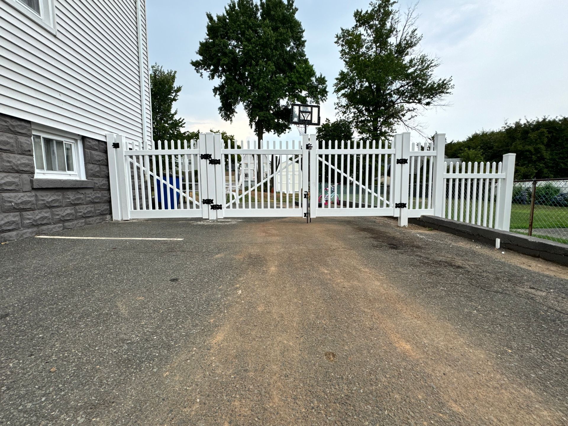A black gate is sitting next to a brick wall.
