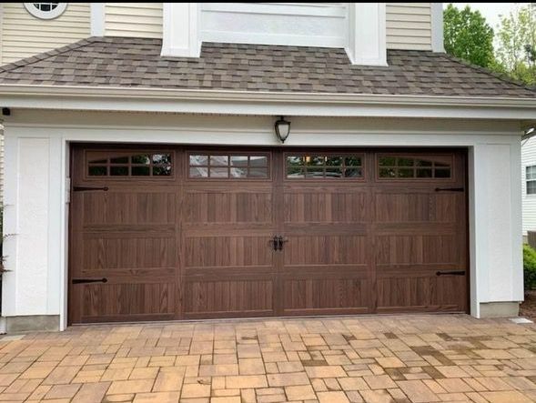 A large brown garage door is sitting in front of a white house.