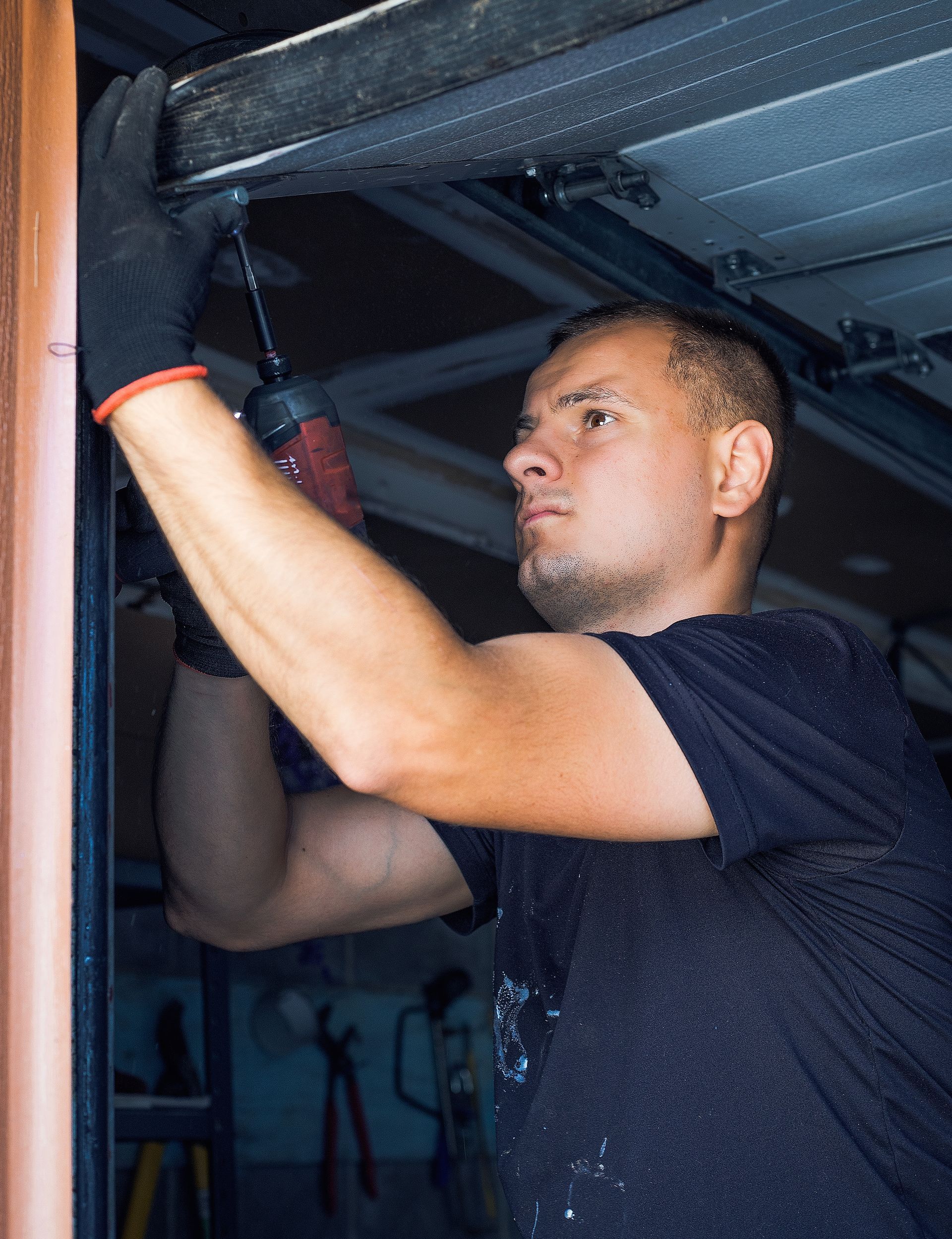 A man is working on a garage door opener. A man is working on a garage door opener.