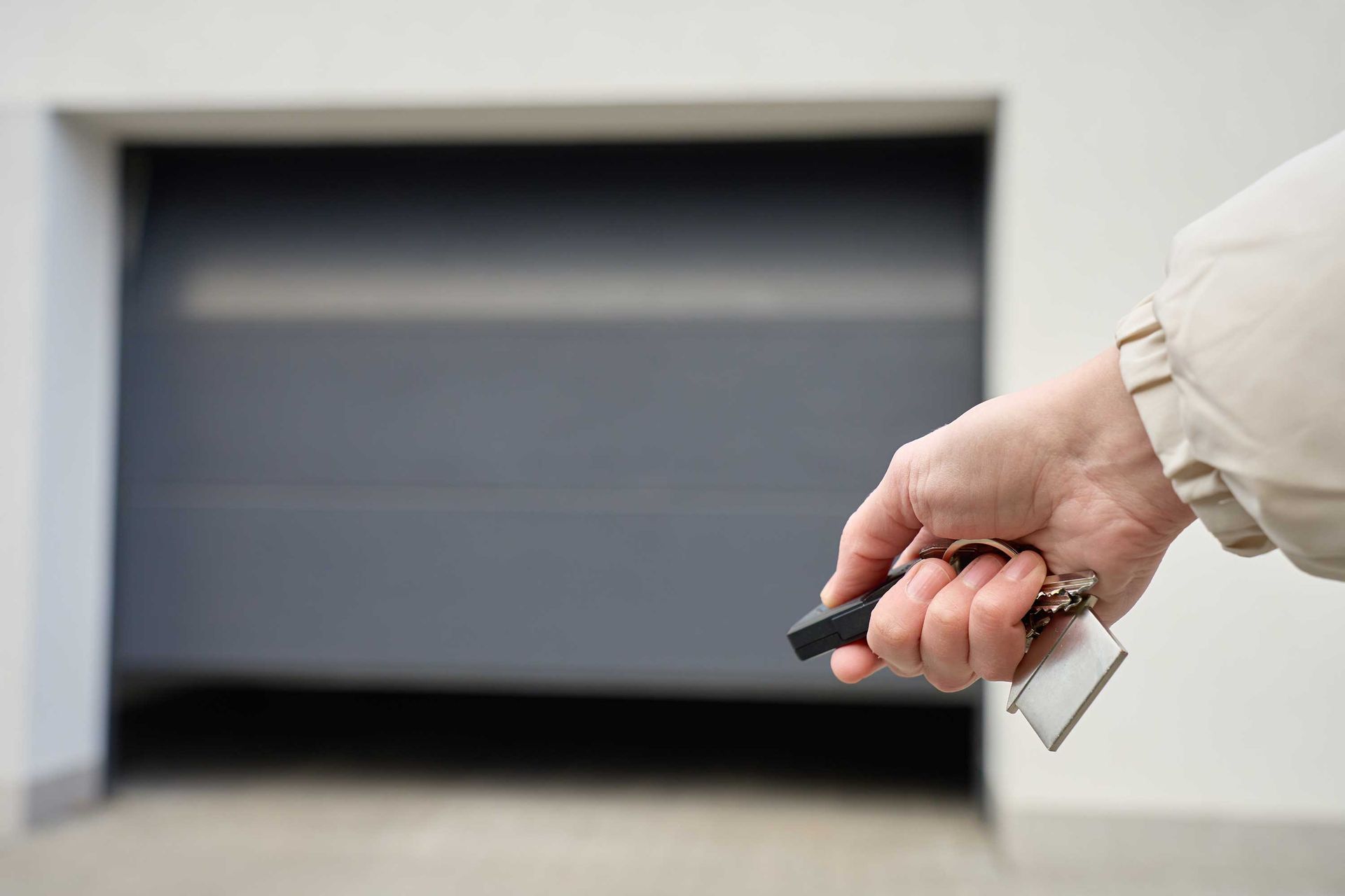 Finger on remote, garage door closed tight, modern home security and convenience.