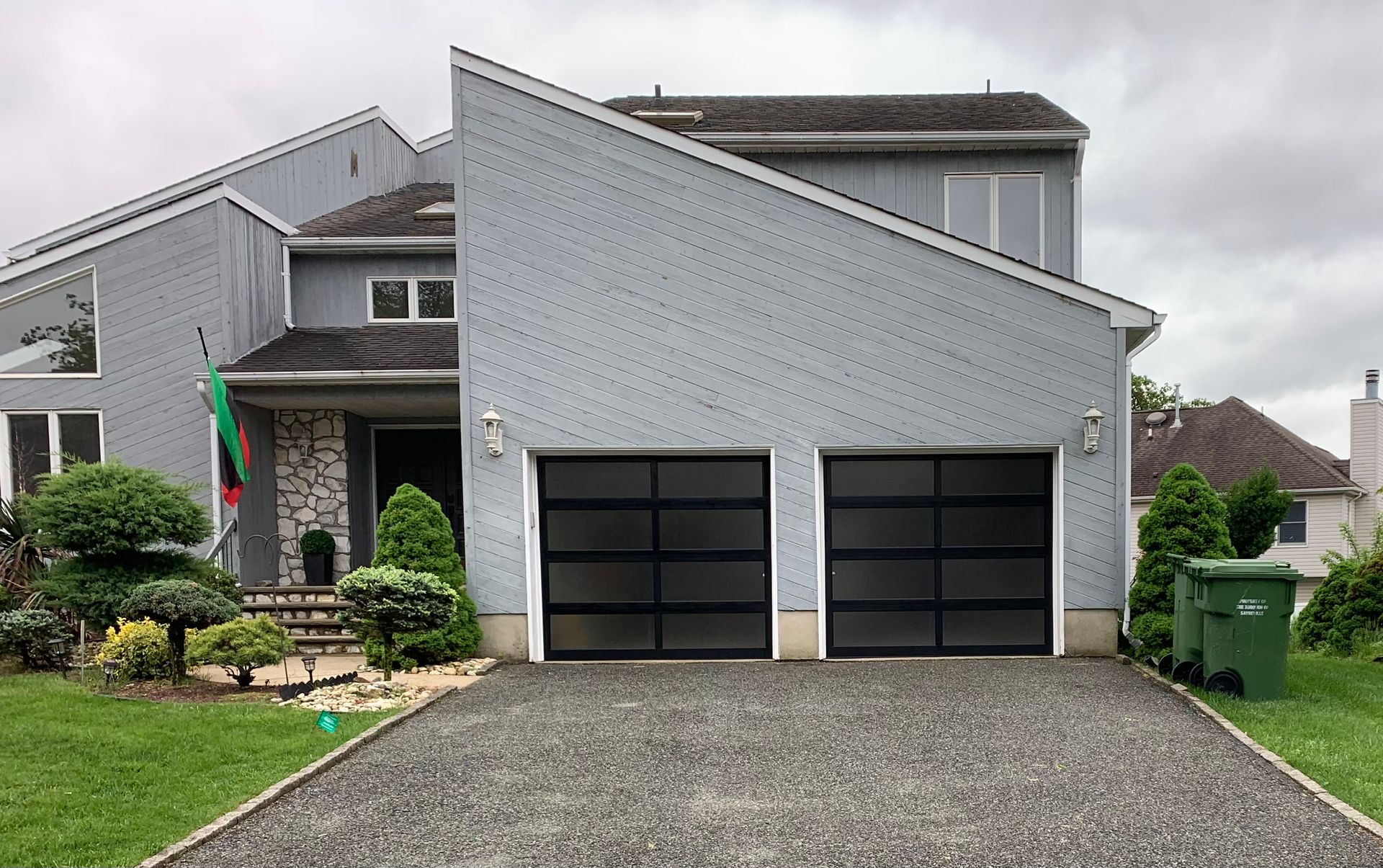 A large house with two garage doors and a gravel driveway.