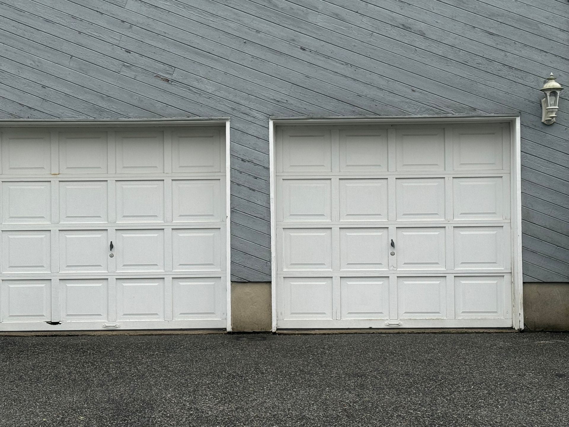 Three white garage doors are lined up in front of a building