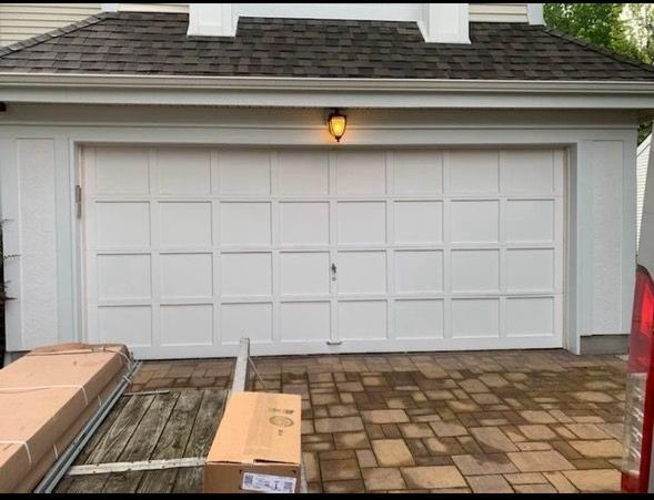 A white garage door with a brick driveway in front of it