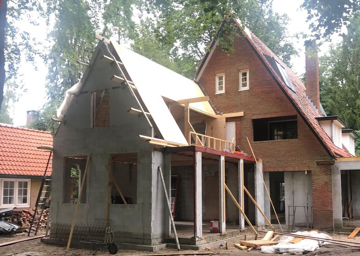 House under construction, with a partially built brick facade and a wooden frame.