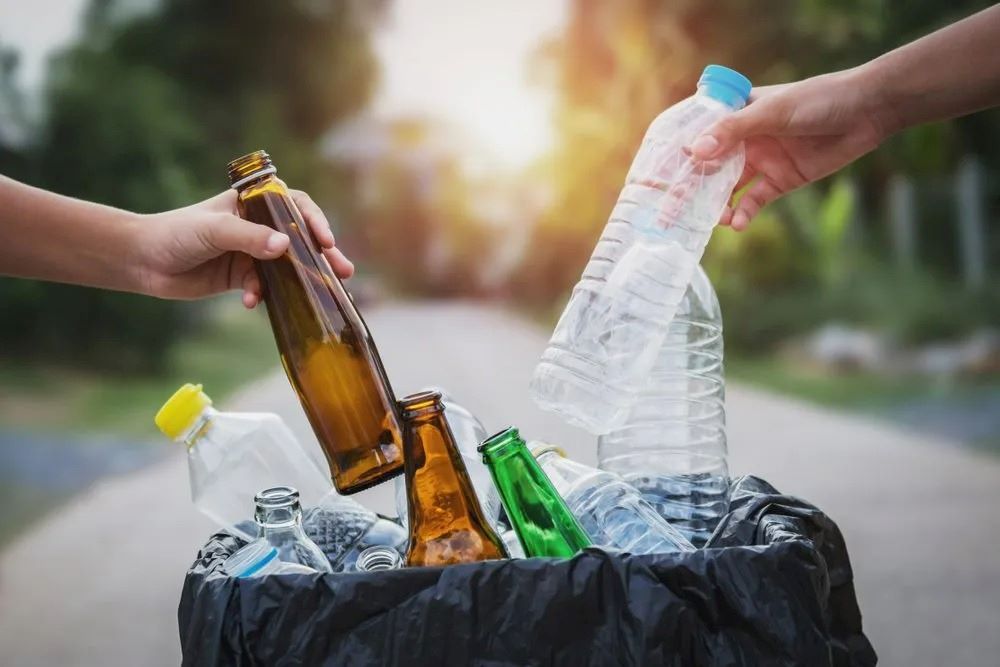 A Person is Throwing Bottles Into a Trash Can — The Territory Can Man In Winnelie, NT