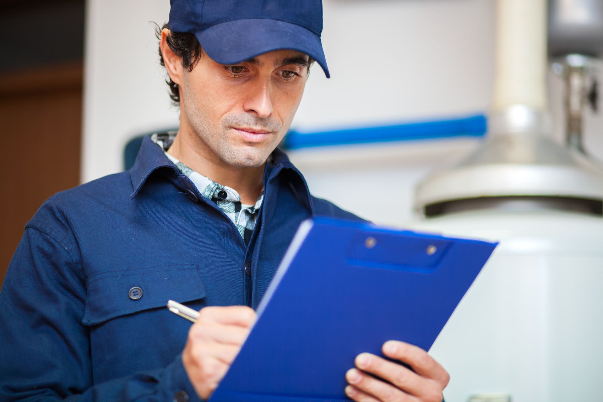 A person in a blue cap writing on a clipboard