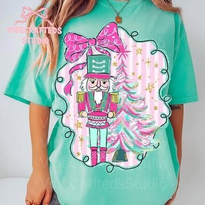 Woman wearing a teal t-shirt with a Nutcracker design inside a pink and teal bow-shaped frame.