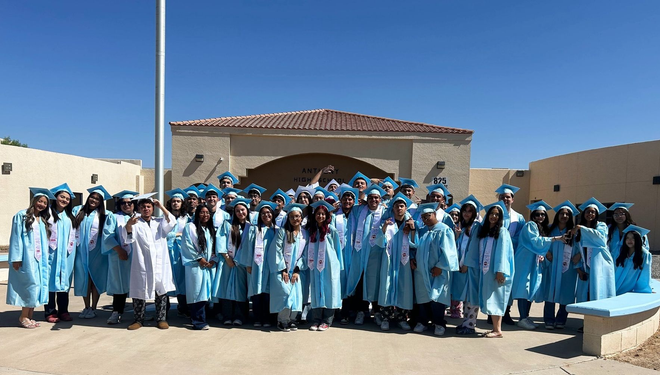 Anthtony High School students dressed in their light blue cap and gown posing as a group outside Anthony High School
