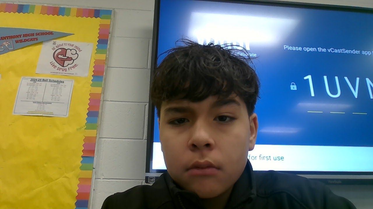 A young boy is standing in front of a screen that says 1uvn